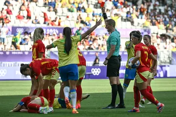 The Norwegian referee brandishes a red card to Marta, who is on the ground, during Brazil's clash with Spain in Bordeaux