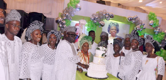 The celebrant, Alhaja Rafatu Anike Ibiladun Adebayo (middle), cutting her 90th birthday cake assisted by her son, Mr Sola Adebayo (4th left), other children and grandchildren