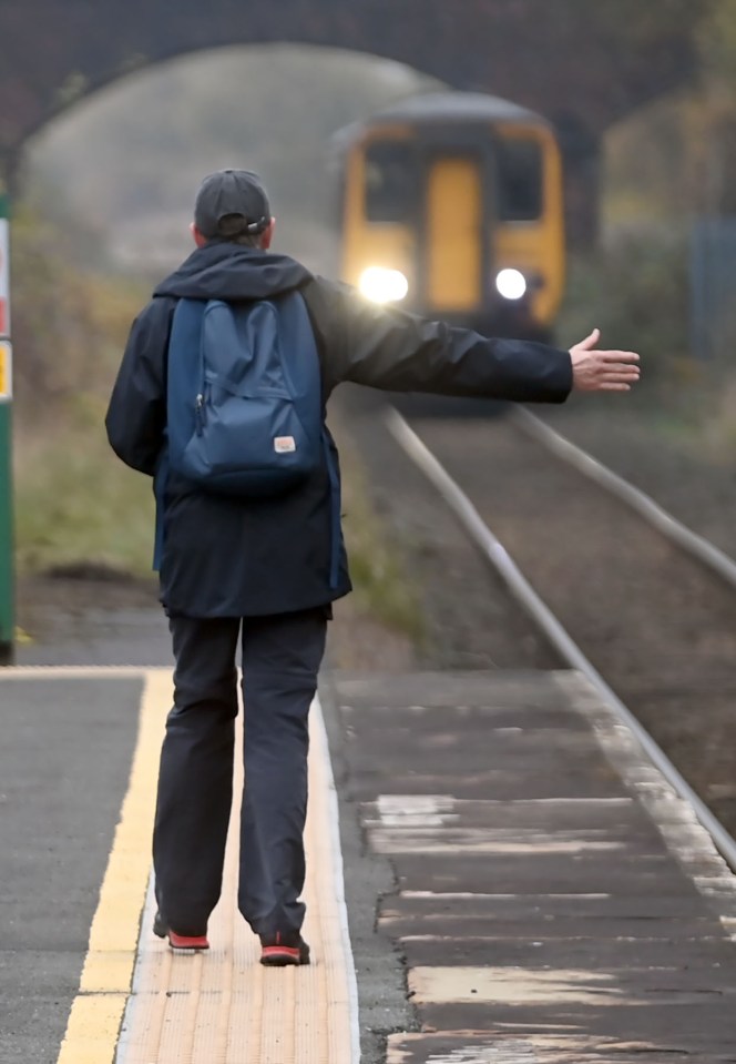 A passenger flags down the once-a-week train, which will not stop if not hailed