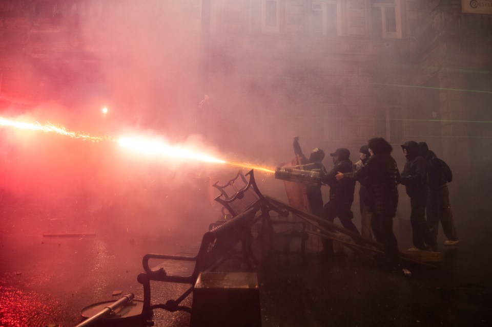 Demonstrators shoot fireworks at the police during a protest outside the parliament