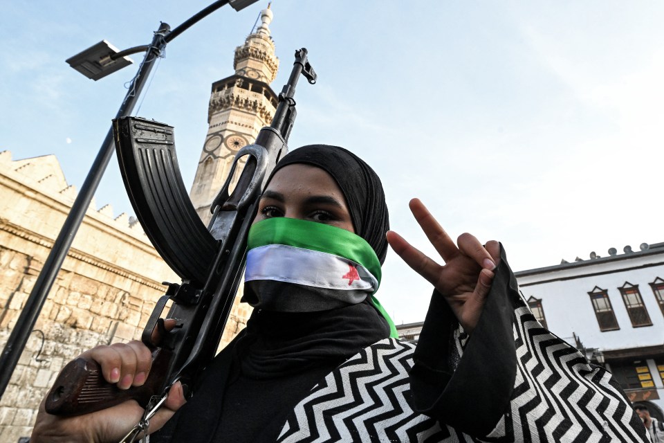 A female rebel fighter makes a victory gesture