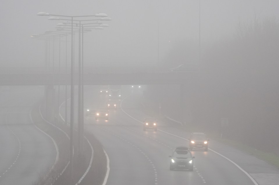 Cars driving in foggy conditions on the M20 near Folkestone in Kent